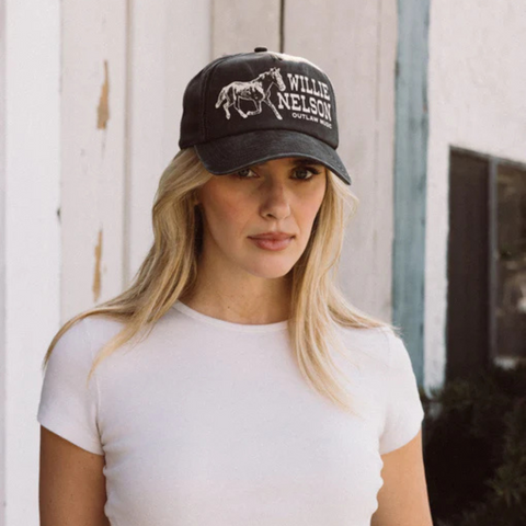 Person wearing the Willie Nelson Walker Hat in Black in a laid-back outdoor setting, styled with vintage flair