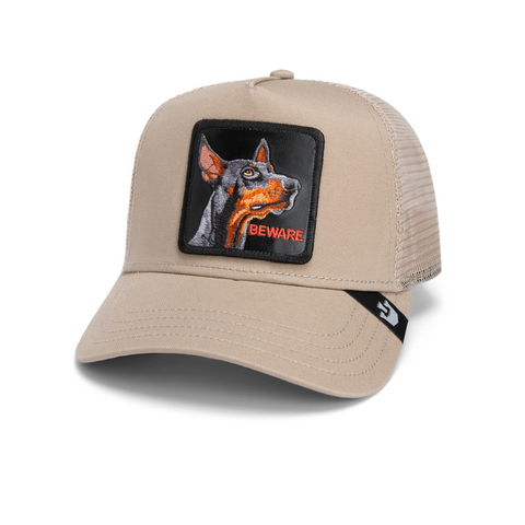 Front view of Goorin Bros' "The Doberman" trucker hat in Oak, showing the structured crown with bold patch featuring a Doberman illustration and breathable mesh back.