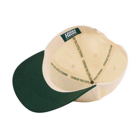 Flat lay of Huega House Athletic Association Hat in Green/Natural highlighting curved brim, embroidered logo, and contrasting crown and visor