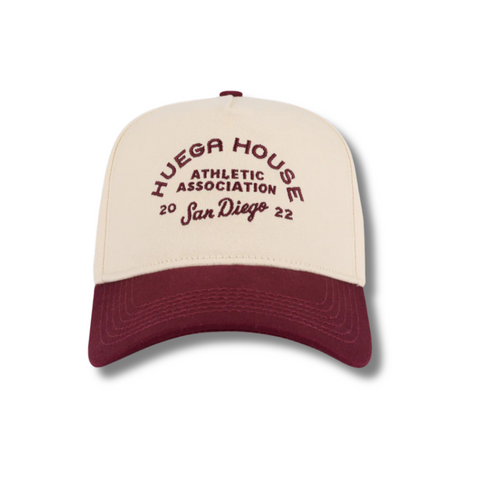 Front view of Huega House Athletic Association Hat in Maroon and Natural featuring vintage-style embroidered “Huega House Athletic Association” logo on a structured maroon crown with a natural curved brim