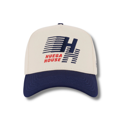 Front view of Huega House Legacy Hat in Navy and Natural featuring embroidered “Huega House Legacy” text on a structured navy crown with a natural curved brim