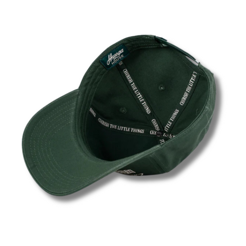 Flat lay of Huega House Moments Hat in Pine Green highlighting tonal embroidery, soft cotton fabric, and structured front panel