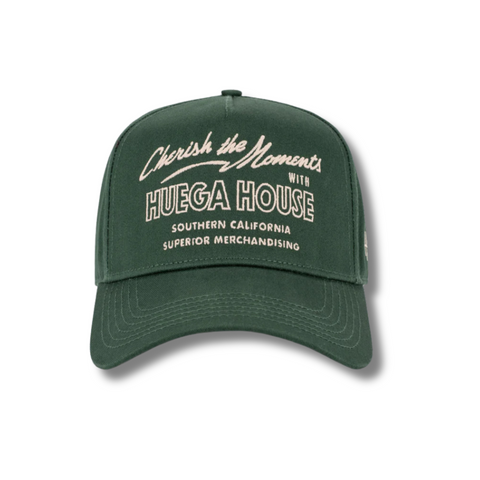 Front view of Huega House Moments Hat in Pine Green featuring clean “Moments” embroidery on a structured crown with a matching curved brim