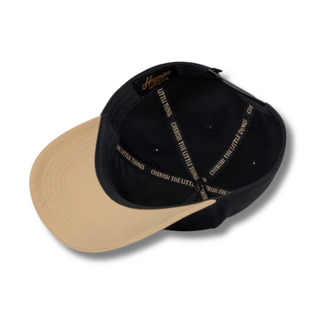 Flat lay of Huega House Vintage Swan Hat in Black/Khaki showcasing embroidered swan patch, black front panel, and contrast khaki brim