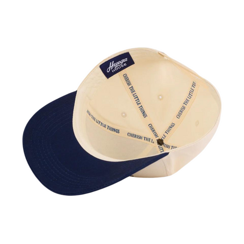 Flat lay of Huega House Vintage Swan Hat in Navy/Natural showcasing the embroidered swan patch, navy crown, and natural curved brim