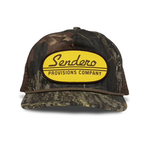 Front view of Sendero Country Store Hat in camo featuring a structured crown, curved brim, and vintage-style embroidered “Country Store” patch
