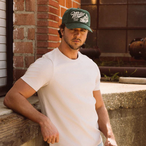 Person wearing the Miller High Life Walker Hat in Bottle green in a casual backyard or tailgate setting