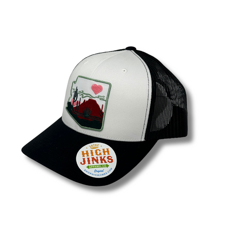 Side angle of the black and white Heart of the Desert Trucker by High Jinks, showing the curved brim and mesh back design.