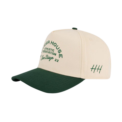 Side view of Huega House Athletic Association Hat in Green/Natural showing two-tone panel construction, breathable fit, and mid-profile shape