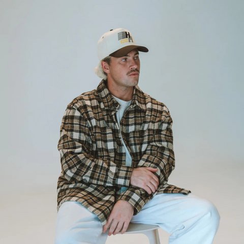 Person wearing the Huega House Legacy Hat in Brown and Natural in a casual, outdoor setting
