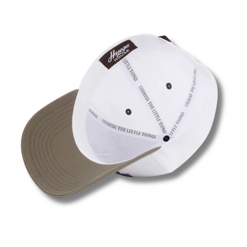 Flat lay of Huega House Legacy Hat in Cement/White highlighting clean embroidered logo, structured crown, and two-tone color scheme