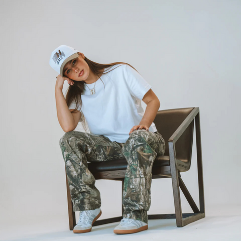 Person wearing the Huega House Legacy Hat in Cement and White in a casual setting with clean, modern styling