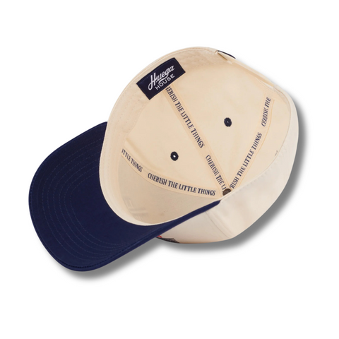 Flat lay of Huega House Legacy Hat in Navy/Natural highlighting tonal logo embroidery, structured navy crown, and natural brim