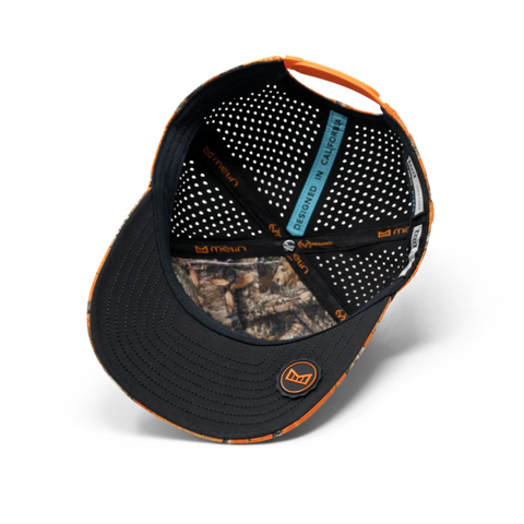 Flat lay of Melin Odyssey Real Tree Hydro Hat in Neon Camo showcasing technical performance fabric, bold camo design, and structured profile