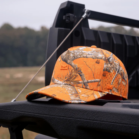 Person wearing the Melin Odyssey Real Tree Hydro Hat in Neon Camo in an active, outdoor adventure setting