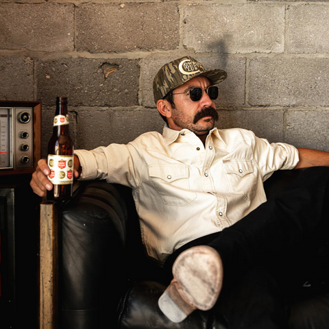 Person wearing the Sendero Cowboy Country Club Hat in Mossy Oak in a rugged, outdoor setting